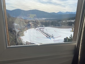 A ski slope with a chairlift, trees, and mountains in the background.