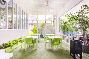 An indoor patio area with tables and chairs, a white fence, and potted plants. - Luxury Deluxe DBL Retreat W/ Free Wifi and Parking (Jakarta)
