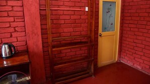 A room with a red brick wall, a wooden door with a glass panel, and a metal rack. - Rokky Hill Cottage Ella (Ella)