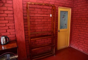 A room with a red brick wall, a wooden door with a glass panel, and a metal rack. - Rokky Hill Cottage Ella (Ella)