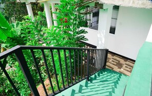 Una escalera con barandilla negra que lleva a una habitación con piso verde y paredes blancas.