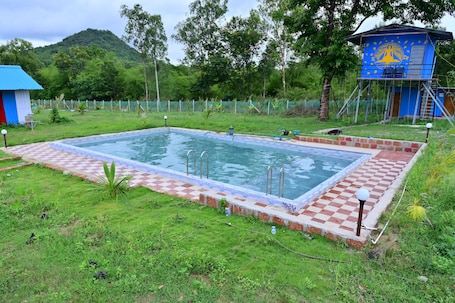 A rectangular pool with a checkered border, surrounded by grass and trees.. Hidden Hills