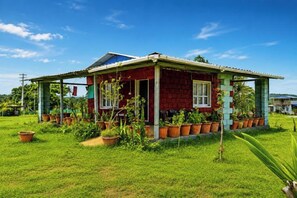 A single-story house with a porch, surrounded by a well-maintained lawn and potted plants. - Hidden Hills (Bylakuppe)