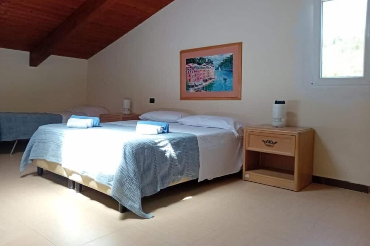 Ein Schlafzimmer mit einem Bett, Nachttischen, einem Fenster und einem Gemälde an der Wand.