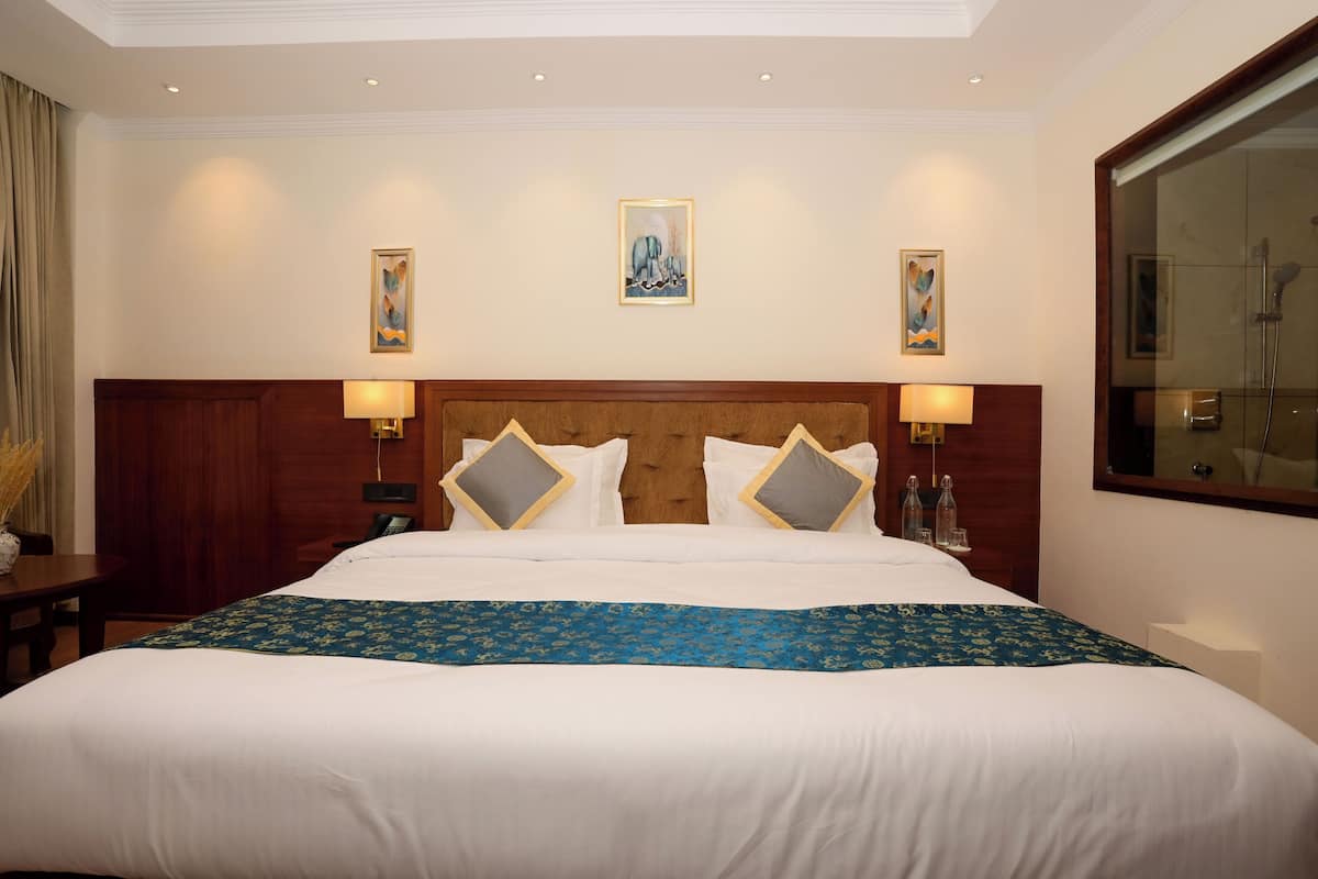 A hotel room with a large bed, two bedside tables, a wooden headboard, and wall-mounted artwork.