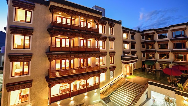 Un hotel de varios pisos con balcones, una escalera y mobiliario exterior.