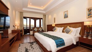 Habitación de hotel con una cama grande, televisión, escritorio y vistas a las montañas.