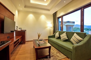 A modern living room with a green sofa, wooden coffee table, and a flat-screen TV.