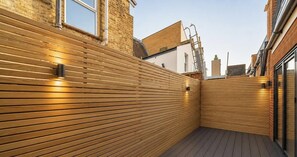 A wooden deck with a slatted wall and a metal ladder. - Exclusive 2 Bedroom House in Catford! (London)