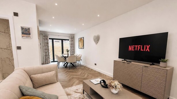 En moderne stue med sofa, sofabord, fjernsyn og spiseplads.