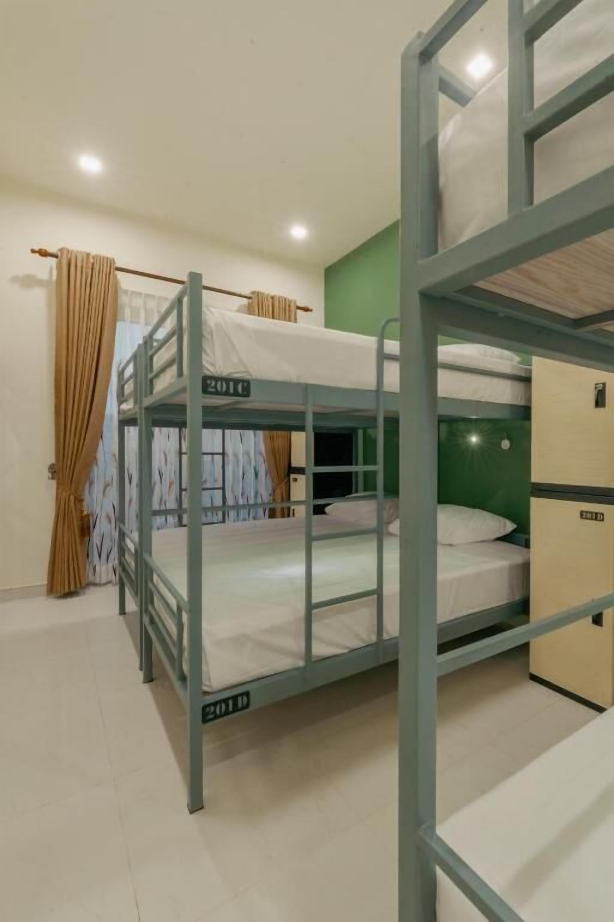 A bunk bed room with a green wall, a window with curtains, and a visible door.