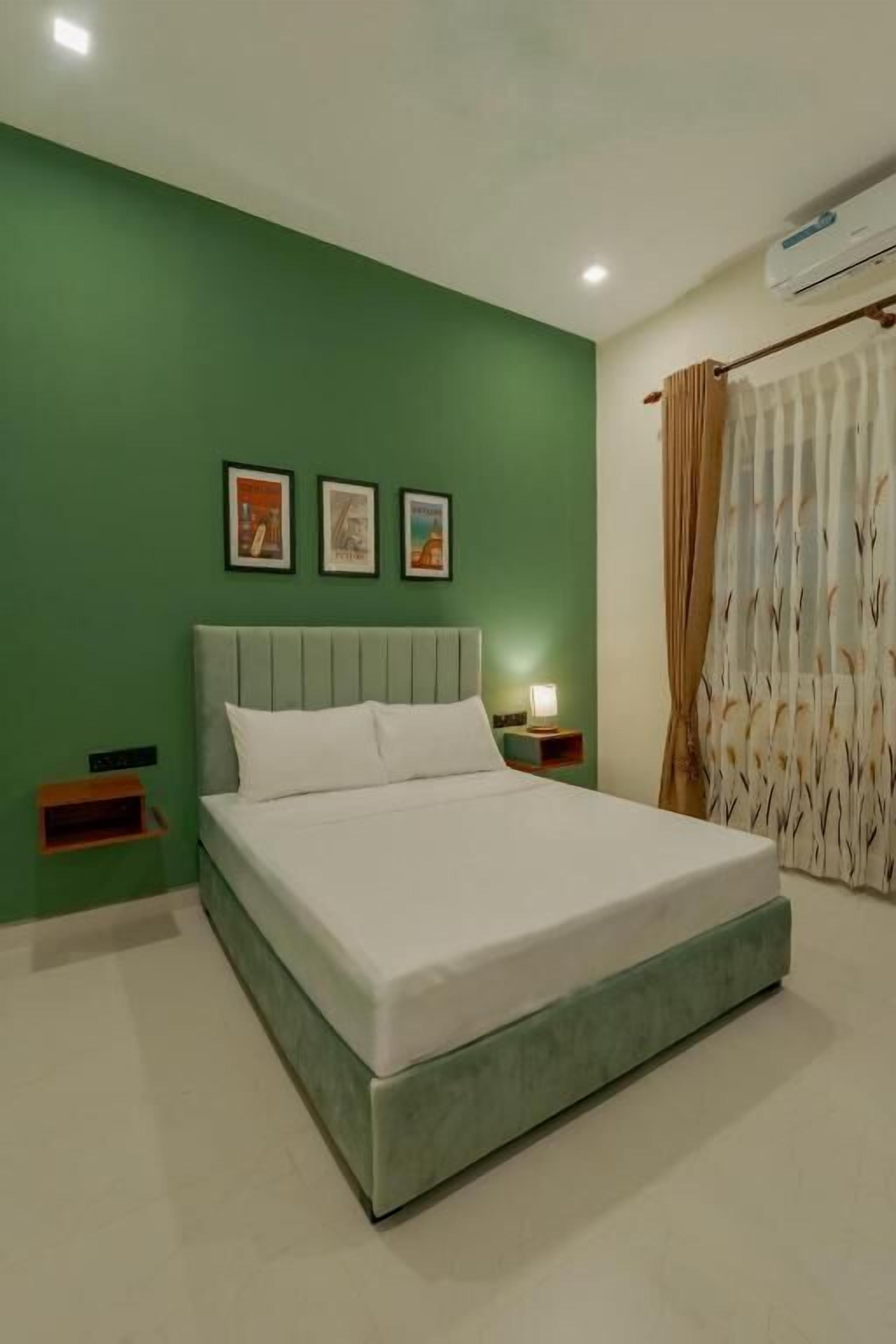 A bed in a room with green walls, a headboard, and a nightstand with a lamp.