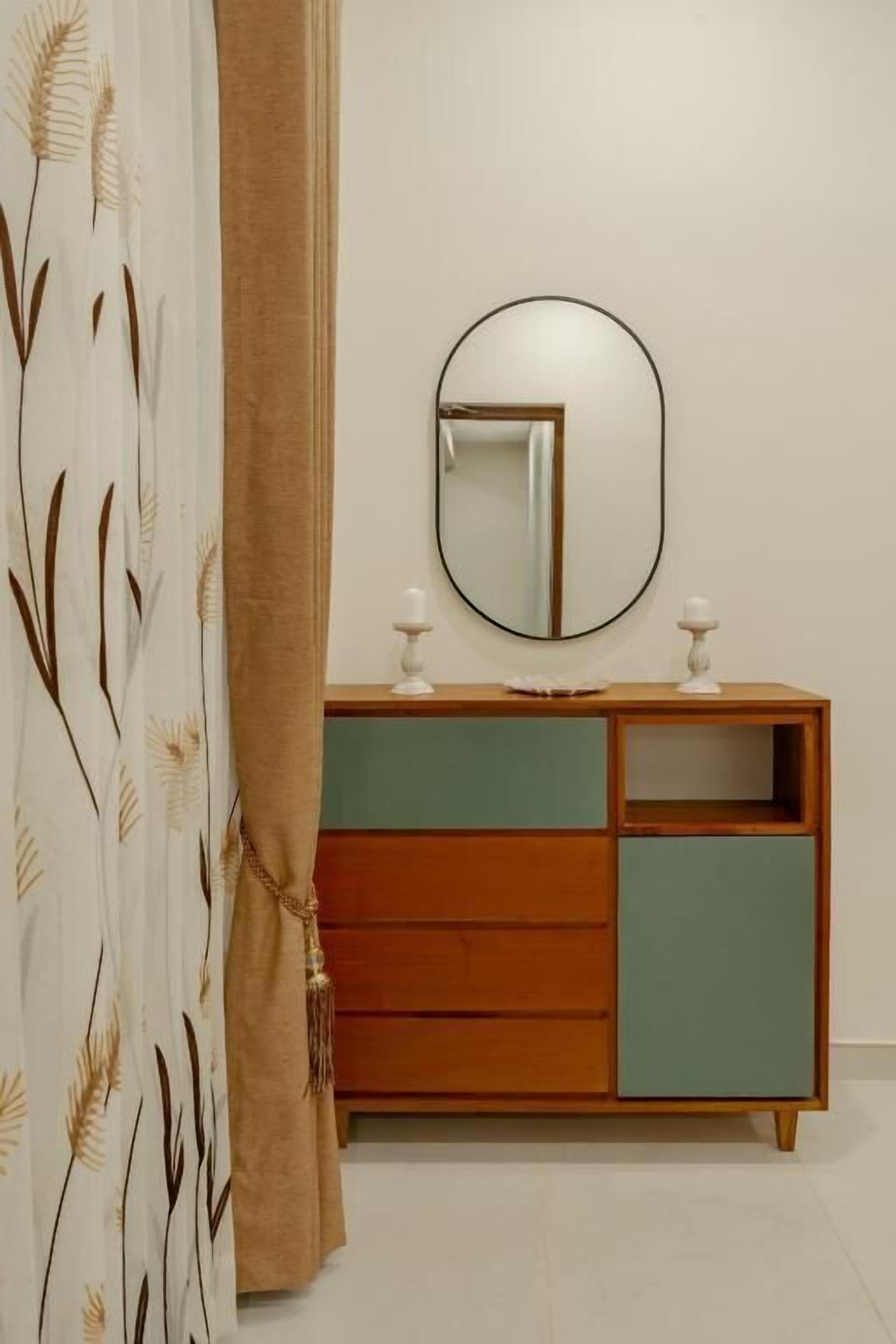 A bathroom with a wooden vanity, a round mirror, and a green cabinet.