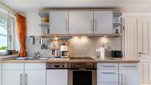 A modern kitchen with white cabinets, a built-in oven, and a coffee maker. - Apartment "Kiel" with Shared Terrace, Garden, and Wi-Fi (Pellworm)