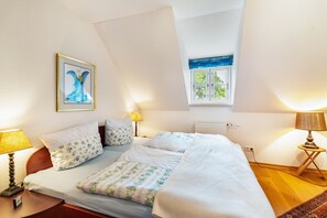 Une chambre à coucher avec un lit, deux lampes de chevet, une fenêtre donnant sur un beau paysage et un tableau encadré au mur.