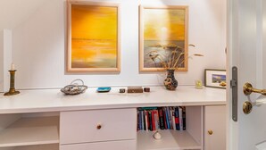 A white desk with two framed paintings, a candle, a vase with dried plants, and a small framed picture. - Apartment "Kiel" with Shared Terrace, Garden, and Wi-Fi (Pellworm)