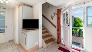 A compact living space with a television, a staircase, and a door leading to an outdoor area. - Apartment "Kiel" with Shared Terrace, Garden, and Wi-Fi (Pellworm)