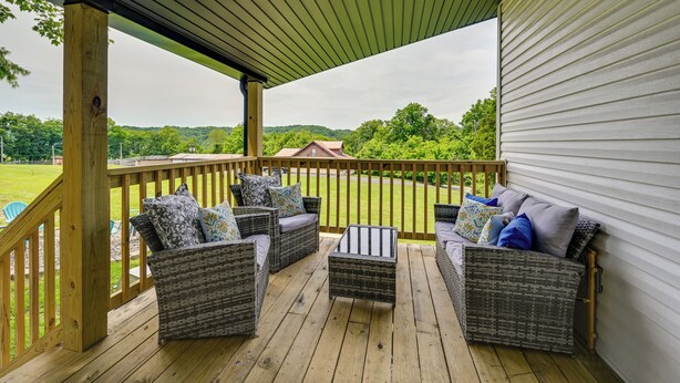 Eine überdachte Terrasse im Freien mit Korbmöbeln und Blick auf eine grüne Landschaft.