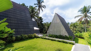 Un edificio moderno con techo oscuro, rodeado de exuberante vegetación y palmeras.