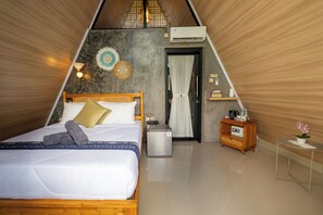 Una habitación triangular con cama, mesita de noche y un pequeño armario.