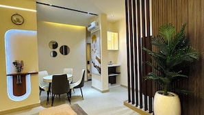 Un interior moderno con sofá, zona de comedor y una planta grande en maceta.