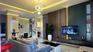 Una sala de estar moderna con un sofá gris, una mesa de centro y un televisor montado en la pared.