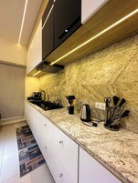 Uma cozinha moderna com bancadas de granito, eletrodomésticos de aço inoxidável e uma coifa preta.
