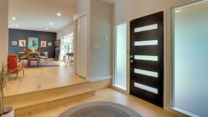 A modern interior with a staircase leading to a dining area, a black door with horizontal stripes, and a light-colored wall. - 5BR Group Retreat w/ Pool in Austin, 4 Mi to Dtwn (Austin)