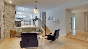 A modern living room with a fireplace, a staircase, and a view of the kitchen. - 5BR Group Retreat w/ Pool in Austin, 4 Mi to Dtwn (Austin)