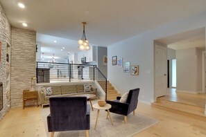Ein modernes Wohnzimmer mit Kamin, einer Treppe und Blick zur Küche.