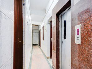 Ein Korridor mit gefliesten Wänden, einem Marmorboden und Türen mit digitaler Anzeige.