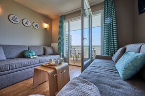 A modern living room with a sofa, a coffee table, and a small table with a teapot and cups. There are three wall-mounted circular decorations and a window with curtains. - Stunning River View Apartment for 5 (Courseulles-sur-Mer)