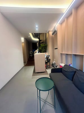 Ein modernes Wohnzimmer mit einer Couch, einem kleinen runden Tisch und einer Treppe, die in eine obere Ebene führt.