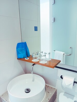 Ein Badezimmer mit einem weißen Waschbecken, einem Spiegel, einem Handtuchhalter und einer blauen Tasche auf der Ablagefläche.