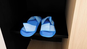 Ein Paar blaue Sandalen mit dem Schriftzug 'blue' am Riemen, auf einer schwarzen Oberfläche platziert.