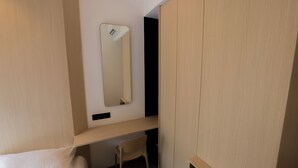 Ein Hotelzimmer mit Bett, Schreibtisch, Stuhl, Kleiderschrank und Spiegel.