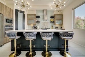 A modern kitchen with a central island, bar stools, built-in appliances, and a large window. - EP Oasis w/ Pool & Spa, Near I-10 & Hospitals (El Paso)