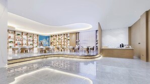 Una hall d'hotel moderna con una reception a forma di arco, zona salotto e scaffali.