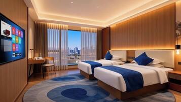 Ein Hotelzimmer mit zwei Betten, einem Fernseher, einem Schreibtisch und Blick auf die Stadt.