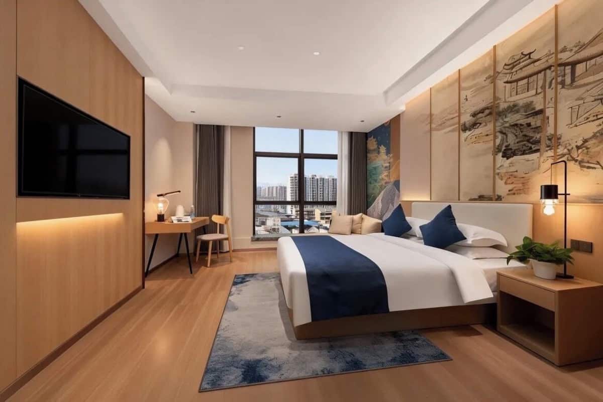 Una habitación de hotel moderna con una cama grande, un escritorio, un televisor y vistas a la ciudad.