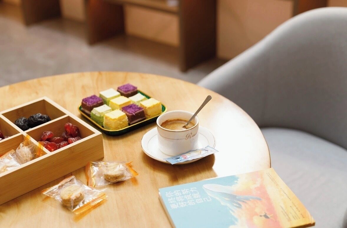 Una mesa con una taza de café, un libro y varios aperitivos.