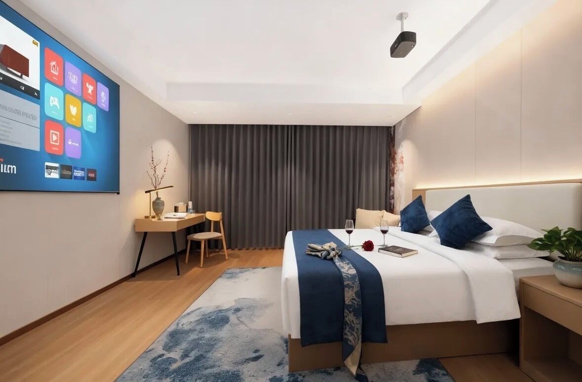 Una habitación de hotel moderna con una cama grande, una mesita de noche, un escritorio con una silla, una pantalla de televisión y un amplio ventanal con cortinas.