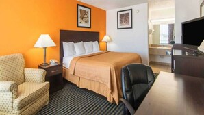 Une chambre d’hôtel équipée d’un lit, d’un bureau, d’une chaise, d’une lampe et d’un téléviseur.