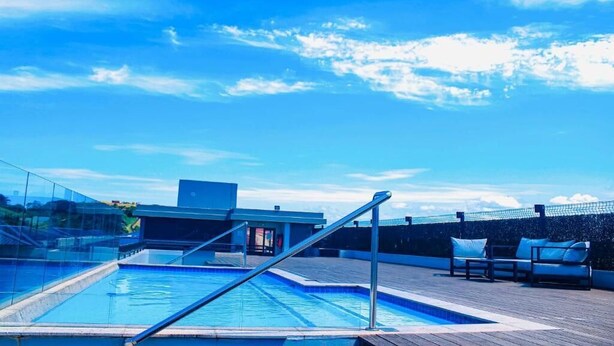 A rooftop pool with a glass barrier, a metal railing, and a lounge area with cushions. - Zimbali lakes boulevard edge 103 (Ballito)