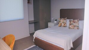 A bedroom with a bed, a nightstand, a chair, and a wardrobe. - Zimbali lakes boulevard edge 103 (Ballito)