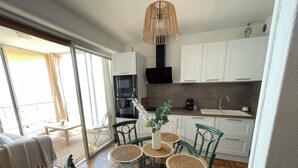 Et moderne køkken med hvide skabe, en sort ovn og en stålvask.