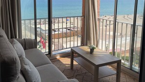 En balkon med udsigt over stranden, en sofa og et lille bord.