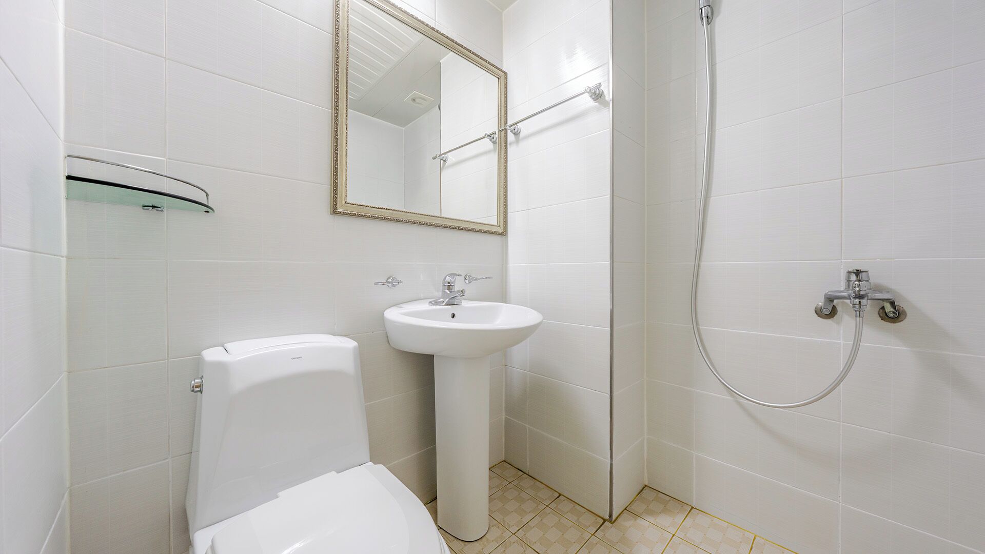 A bathroom with a toilet, sink, mirror, and shower.