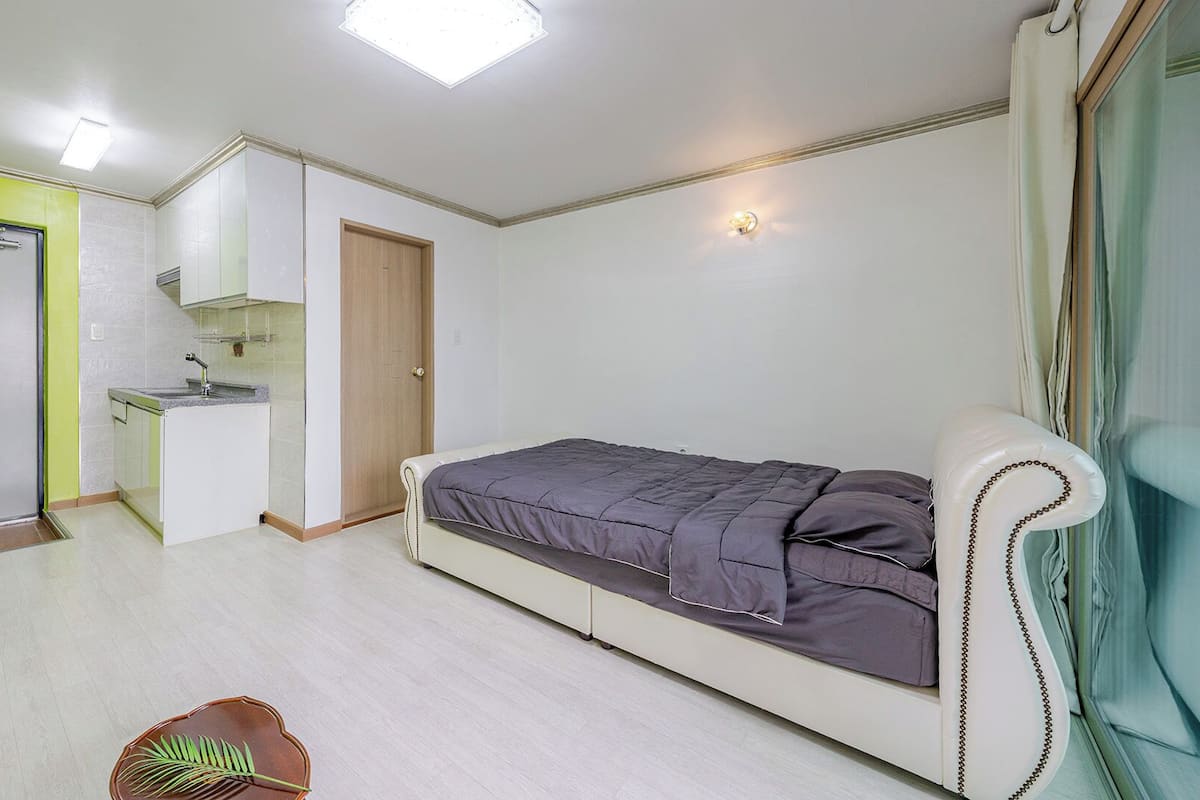 Un dormitorio con cama, kitchenette pequeño y baño.