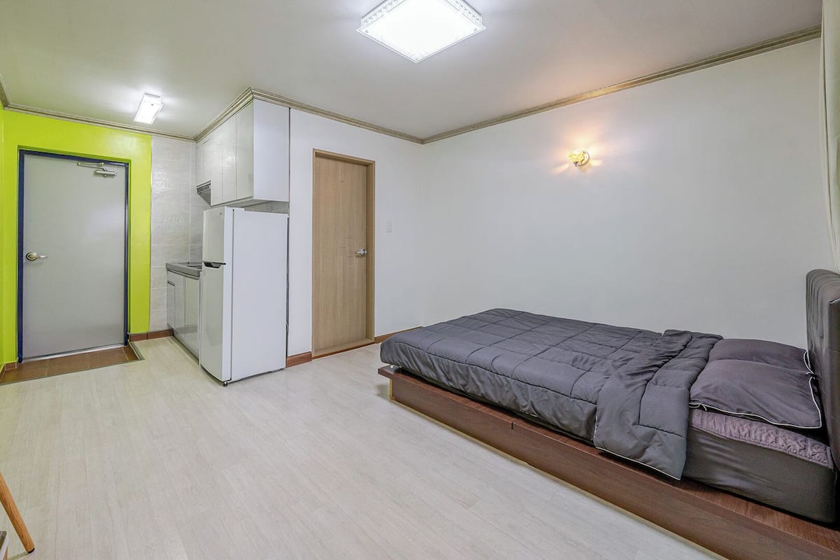 Un dormitorio con cama, televisión, armario y puerta.